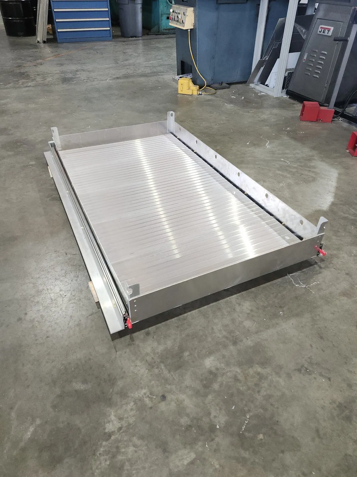 A fabricated aluminum ramp deck with extruded planking and side rails, laid flat on the shop floor.