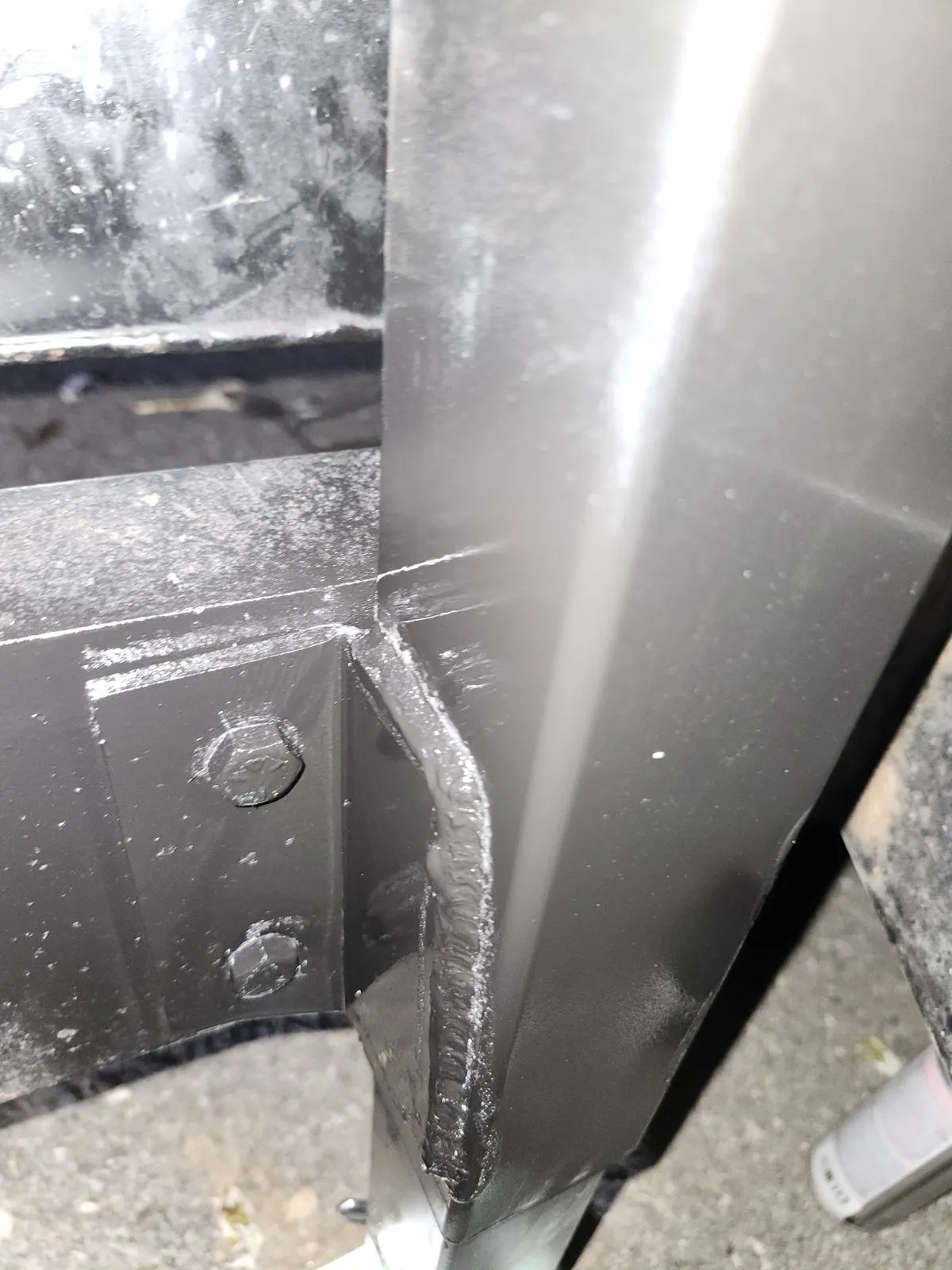 A TIG-welded corner joint on an aluminum trailer frame, the bead running up the vertical member.