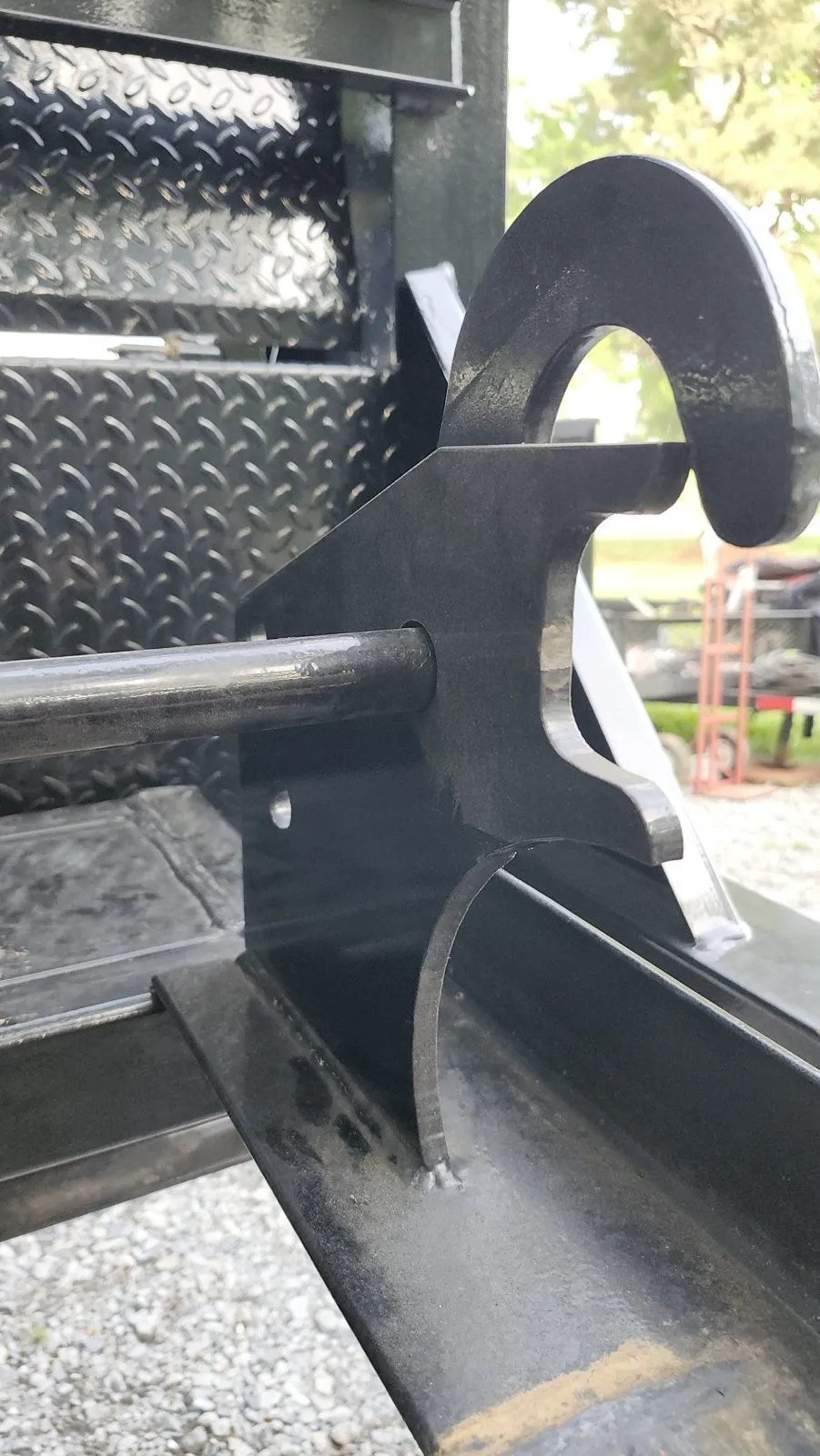 A rebuilt attachment mount plate with a hook tab, welded to a diamond-plate deck on a piece of equipment.
