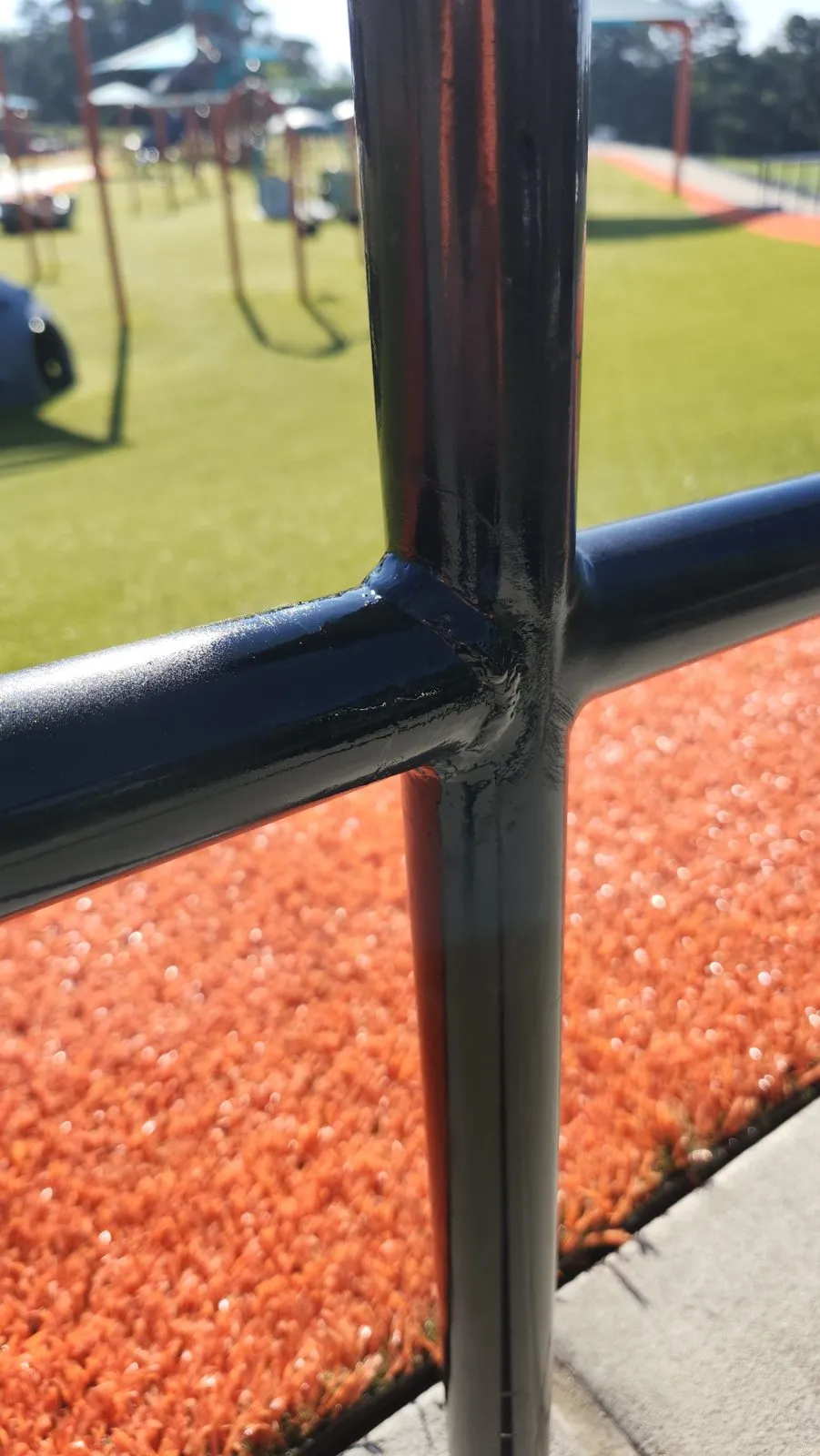 The same rail joint after repair, welded solid and painted black, the orange track beneath it.