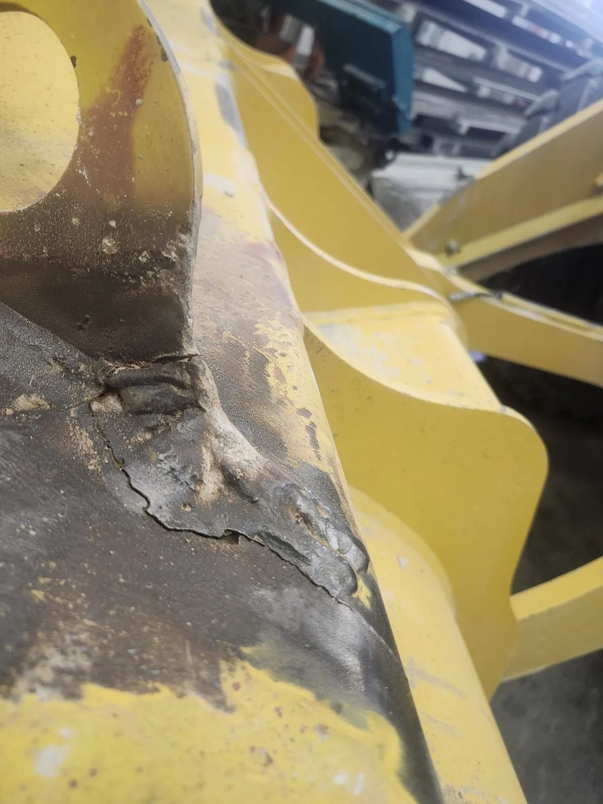 The crack before repair, running through the paint at the joint between a gusset and the bucket wall.