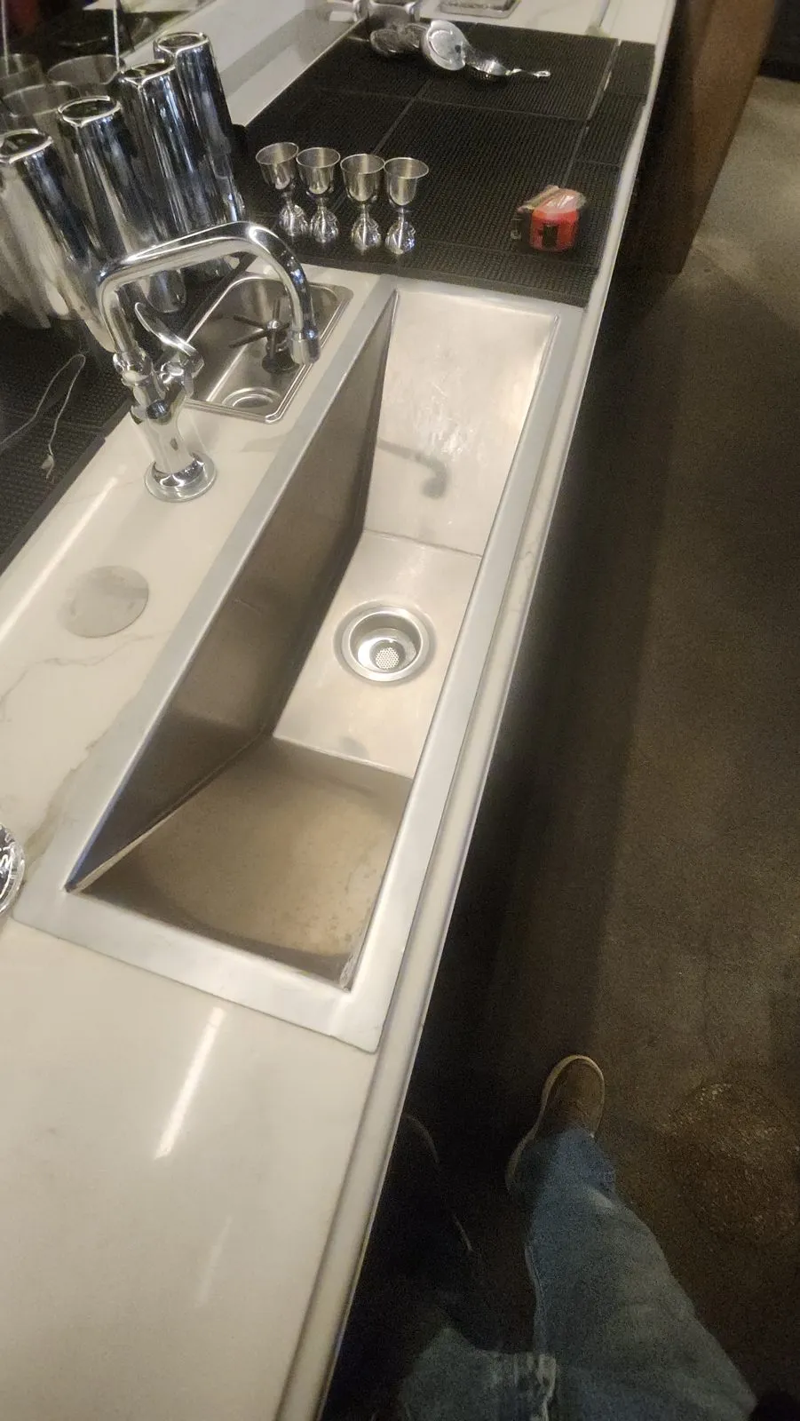 A stainless steel sink and counter section in a commercial kitchen after repair, the surface dressed back smooth.