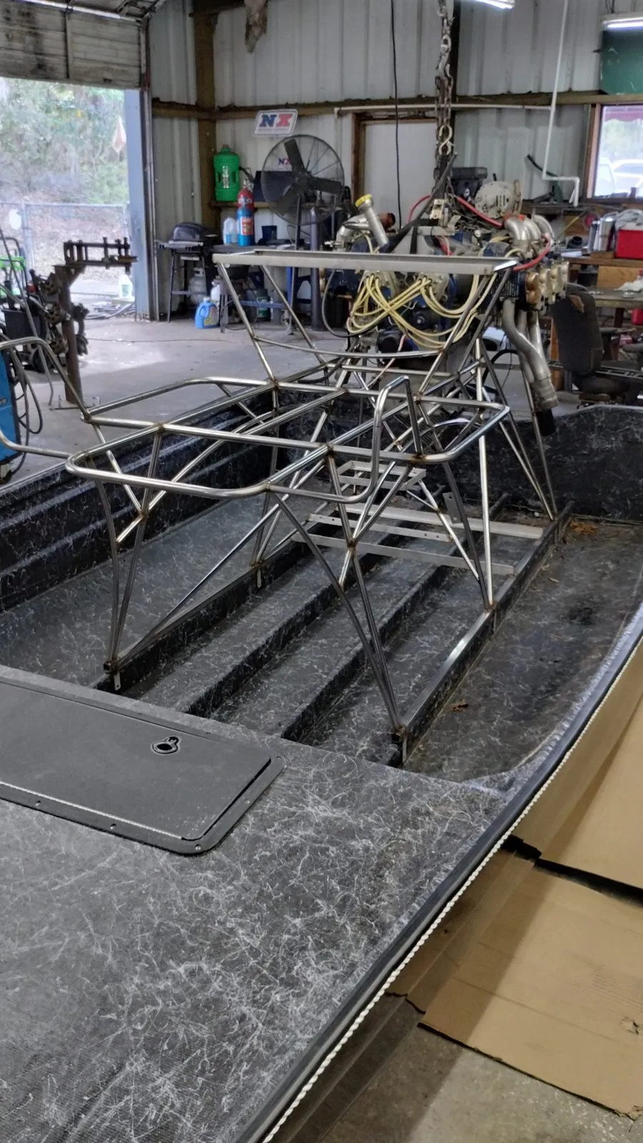 Inside an aluminum jon boat on its trailer, looking toward the stern with the ribs and floor exposed for repair.