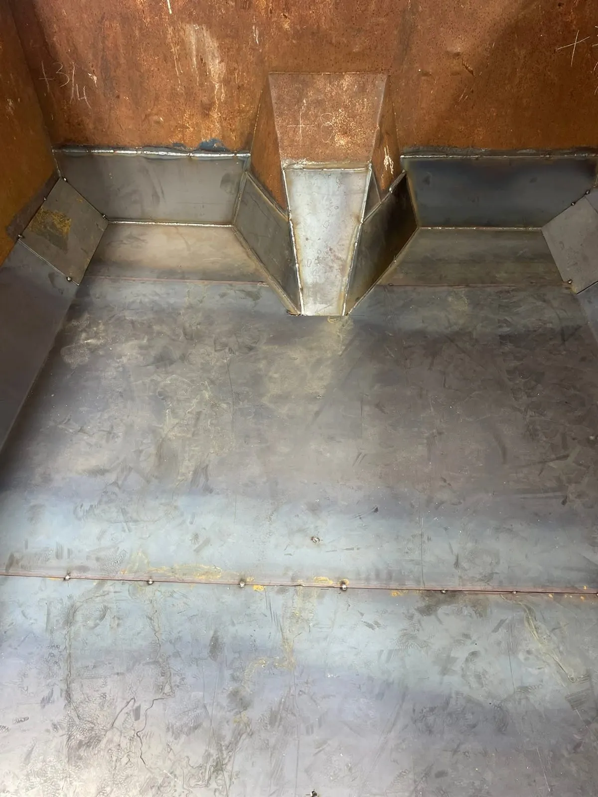 Inside a steel container where new floor plate and corner gusset panels have been welded into the worn walls.