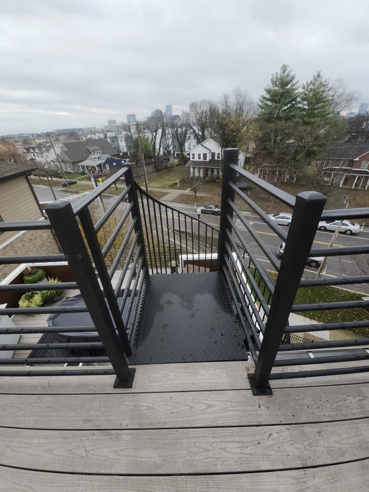 A black metal guardrail and gate on a rooftop deck, looking out over the neighborhood.