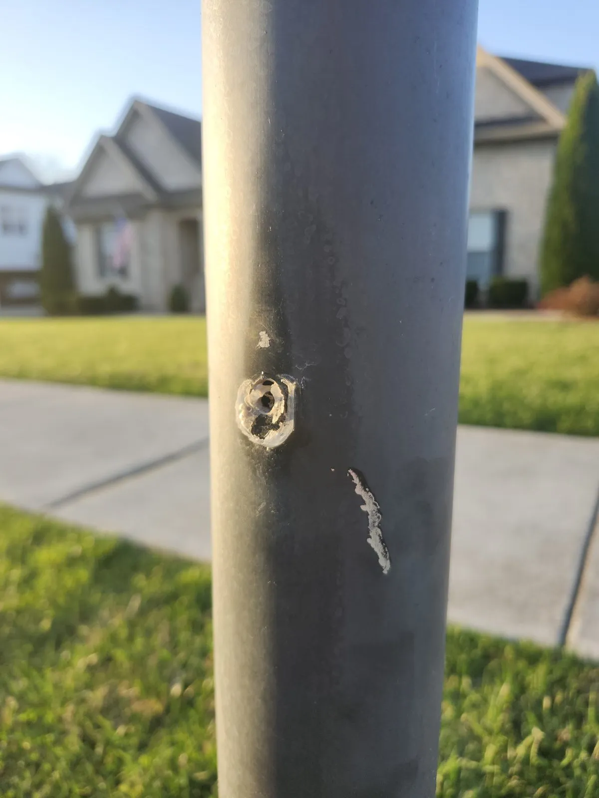 The same steel post before repair, rusted through with a hole and a split below it.
