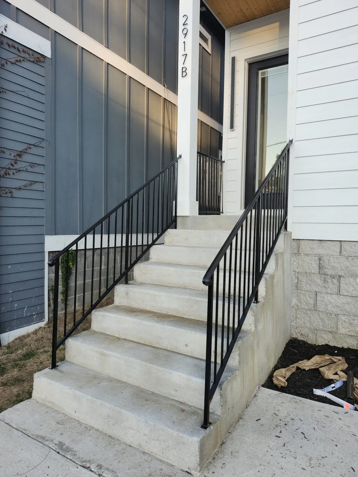 Matching black steel handrails on the concrete front steps of two adjoining townhouses.