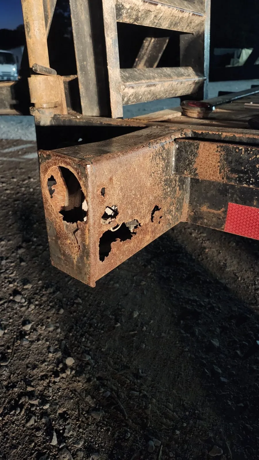 The trailer tongue before repair: the steel channel rusted through with holes along its side.